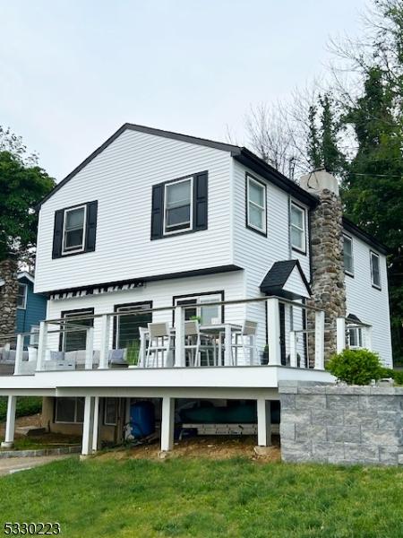 rear view of house with a lawn and a wooden deck