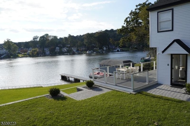 view of dock with a yard and a deck with water view