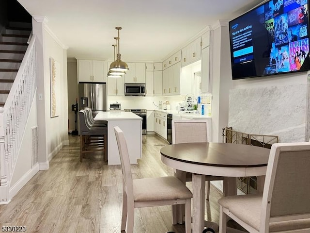 dining area featuring light hardwood / wood-style floors and ornamental molding