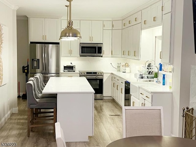 kitchen featuring pendant lighting, a kitchen island, white cabinetry, and appliances with stainless steel finishes