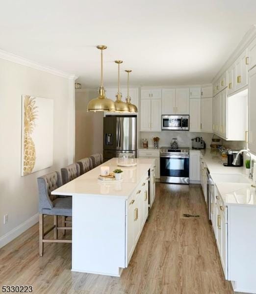 kitchen featuring a center island, white cabinets, pendant lighting, and appliances with stainless steel finishes