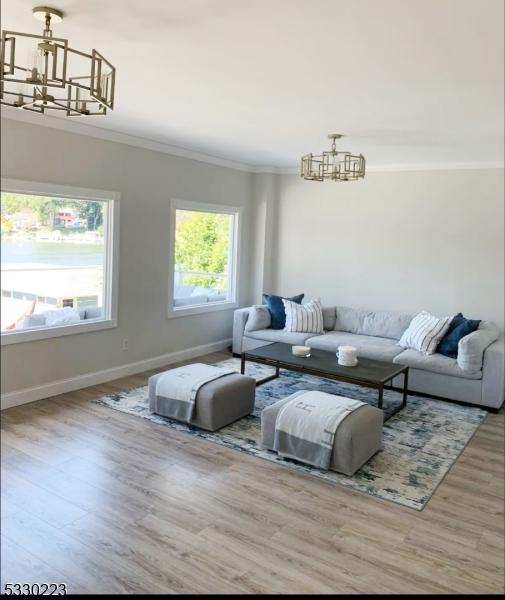 living room featuring crown molding, hardwood / wood-style floors, and a chandelier