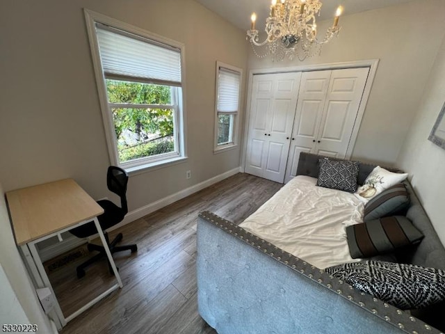 bedroom with hardwood / wood-style flooring, a chandelier, and a closet