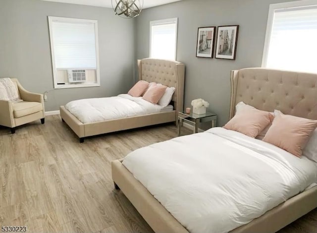 bedroom with light hardwood / wood-style flooring, cooling unit, and a chandelier