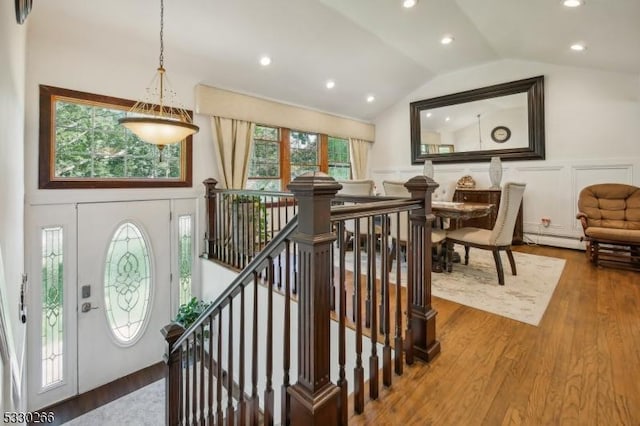 entrance foyer featuring a healthy amount of sunlight, wood-type flooring, lofted ceiling, and a baseboard heating unit