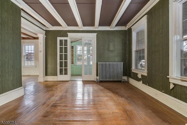 empty room featuring hardwood / wood-style floors, radiator heating unit, french doors, and beam ceiling