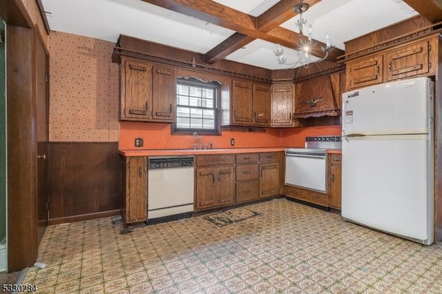 kitchen featuring sink, white appliances, and wood walls