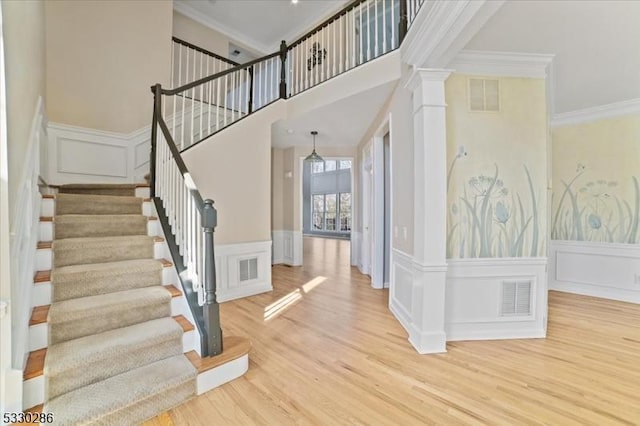 entryway with ornamental molding, visible vents, ornate columns, and wood finished floors