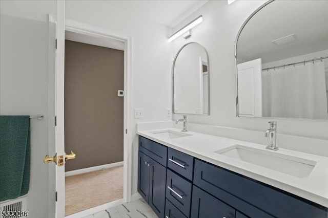 bathroom featuring marble finish floor, double vanity, a sink, and baseboards