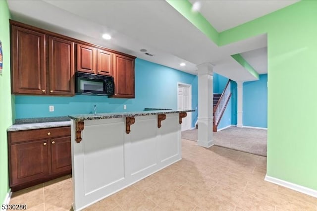 kitchen with baseboards, light stone counters, a kitchen breakfast bar, black microwave, and recessed lighting