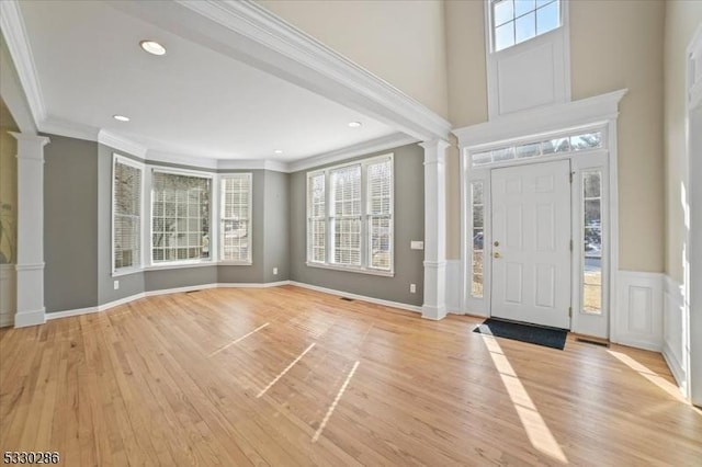 entrance foyer with plenty of natural light, decorative columns, and crown molding