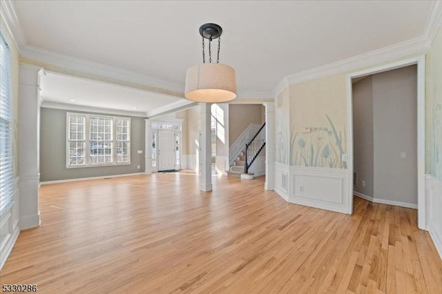 interior space with ornamental molding, stairway, light wood-style flooring, and a decorative wall