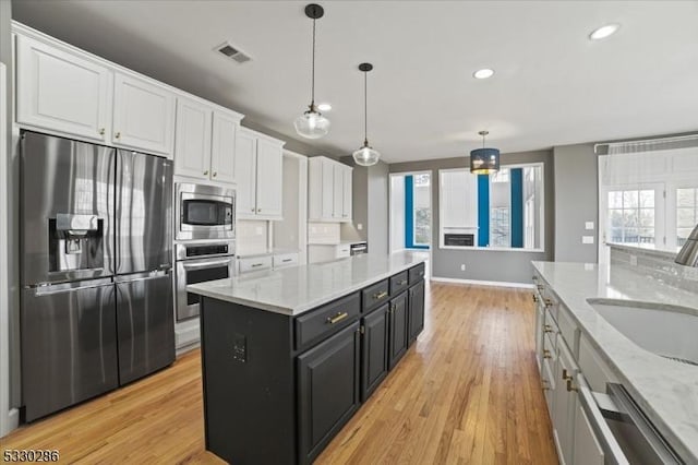 kitchen with dark cabinets, a sink, visible vents, white cabinetry, and appliances with stainless steel finishes