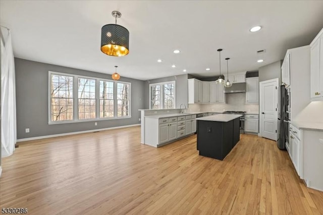 kitchen featuring a kitchen island, freestanding refrigerator, a sink, backsplash, and gas stove