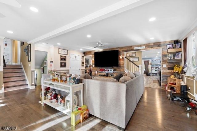 living room with ceiling fan, dark hardwood / wood-style flooring, ornamental molding, and wooden walls