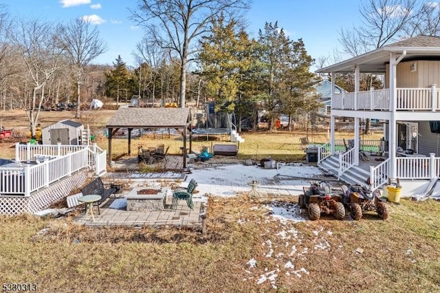 view of yard with a patio, a trampoline, a fire pit, and a shed