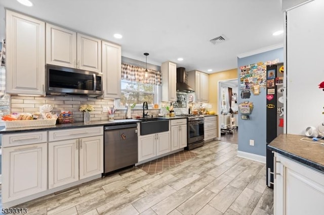 kitchen featuring pendant lighting, sink, wall chimney exhaust hood, tasteful backsplash, and stainless steel appliances