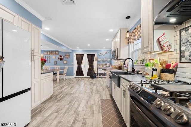 kitchen with sink, stainless steel appliances, extractor fan, decorative light fixtures, and ornamental molding