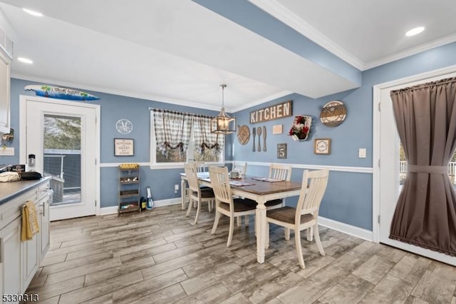 dining space with light wood-type flooring, an inviting chandelier, and ornamental molding