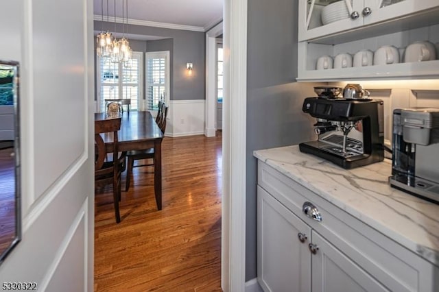 bar with light stone countertops, hanging light fixtures, a notable chandelier, wood-type flooring, and white cabinets