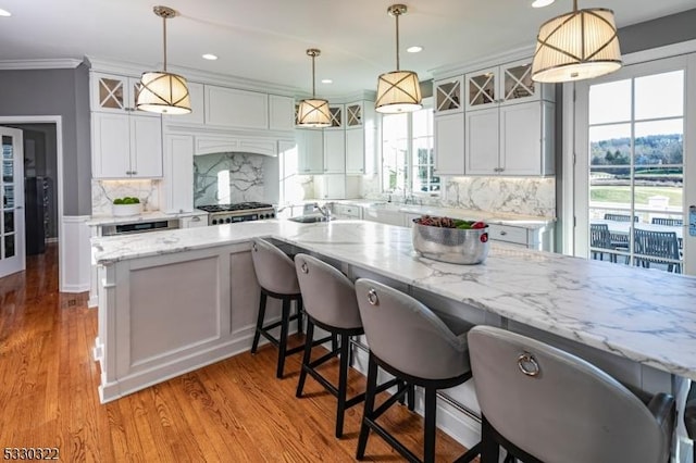 kitchen with decorative backsplash, white cabinetry, and decorative light fixtures