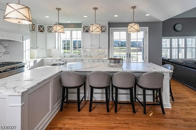 kitchen featuring backsplash, a large island with sink, and pendant lighting