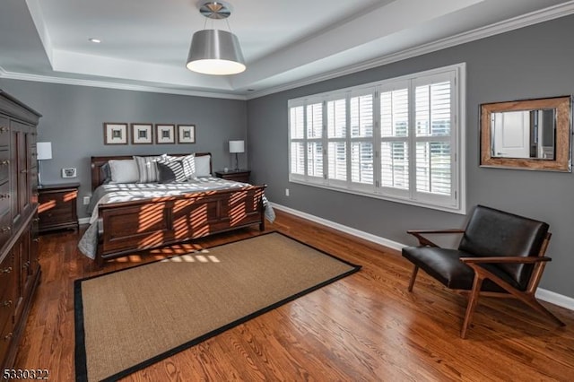 bedroom with dark hardwood / wood-style flooring, crown molding, and a tray ceiling