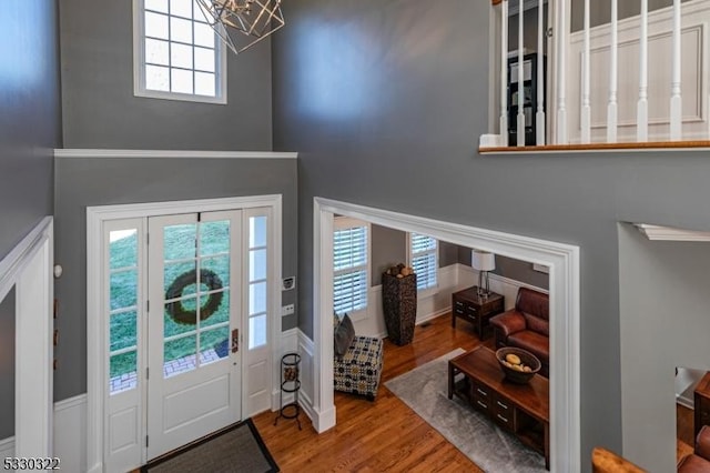 entryway with wood-type flooring, a healthy amount of sunlight, a high ceiling, and an inviting chandelier