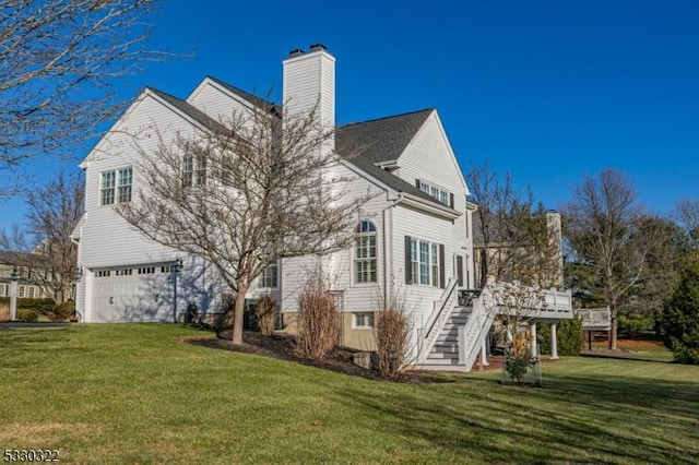 back of property with a garage, a deck, and a lawn