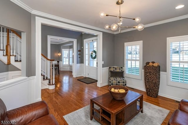 living room featuring a chandelier, wood-type flooring, and ornamental molding