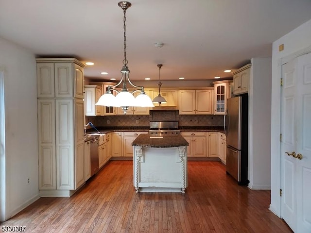 kitchen featuring hanging light fixtures, decorative backsplash, a kitchen island, wood-type flooring, and stainless steel appliances