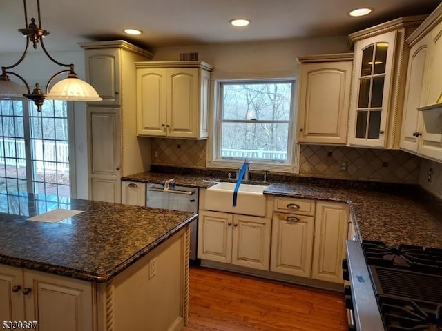 kitchen with decorative backsplash, stainless steel appliances, sink, a notable chandelier, and hanging light fixtures