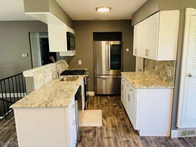 kitchen featuring white cabinets, dark hardwood / wood-style flooring, stainless steel appliances, and light stone counters