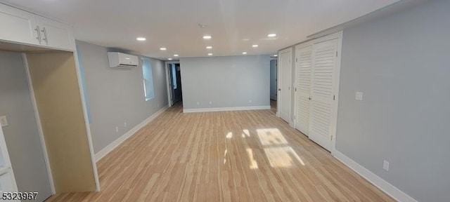 basement featuring a wall mounted air conditioner and light hardwood / wood-style floors