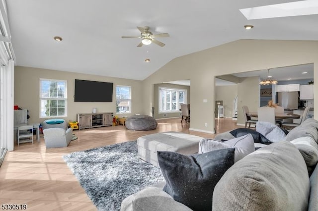 living room featuring ceiling fan with notable chandelier and lofted ceiling with skylight