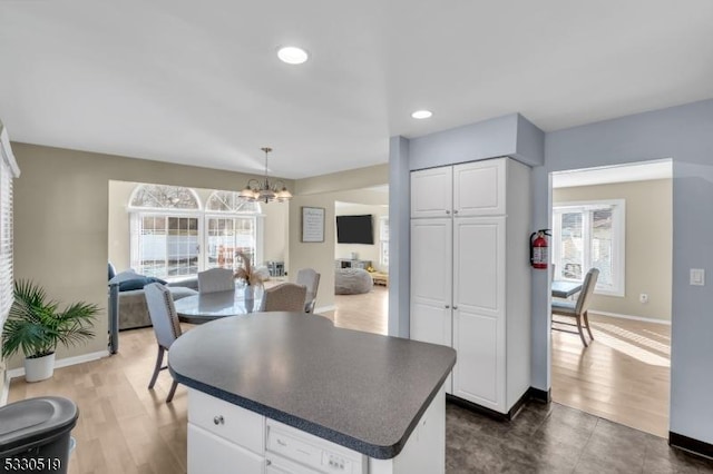 kitchen featuring hanging light fixtures, dark hardwood / wood-style flooring, a kitchen island, white cabinetry, and an inviting chandelier