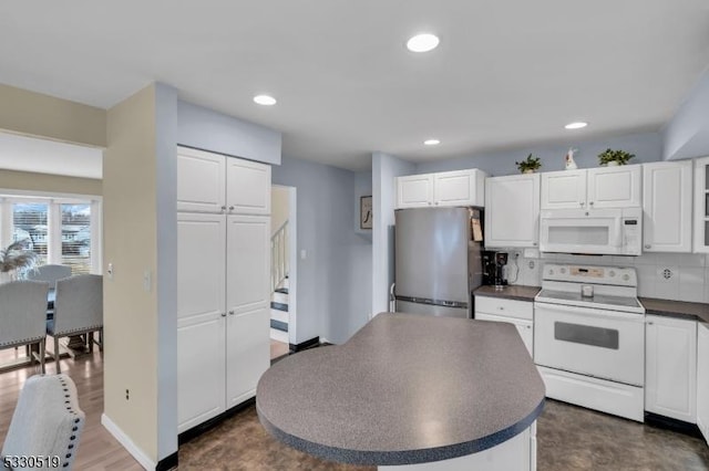 kitchen featuring white appliances, white cabinets, and backsplash