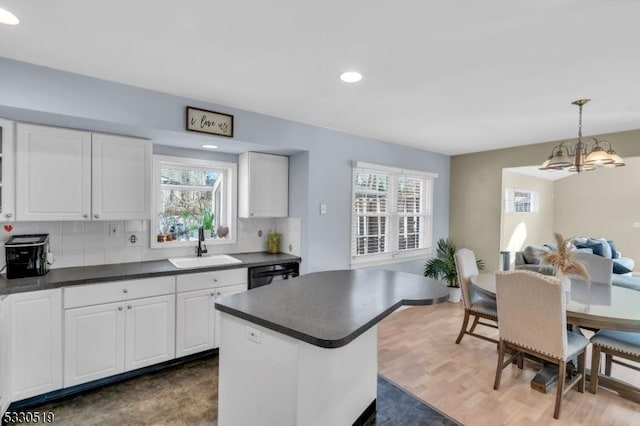 kitchen with white cabinets, decorative light fixtures, backsplash, and sink