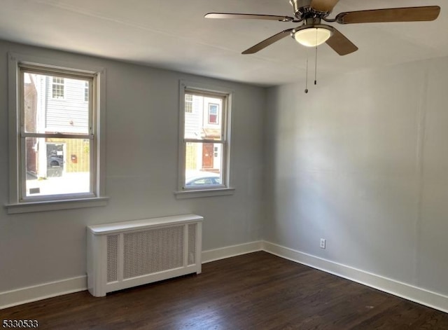 unfurnished room with dark hardwood / wood-style floors, ceiling fan, and radiator