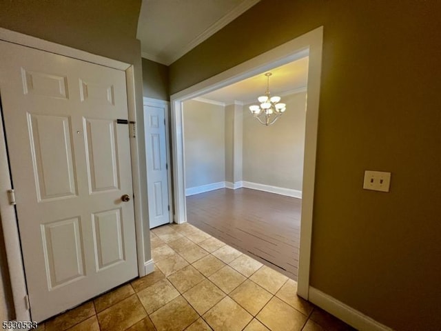 hallway featuring crown molding, light tile patterned floors, and an inviting chandelier