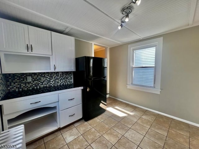 kitchen featuring black refrigerator, white cabinets, tasteful backsplash, and light tile patterned flooring