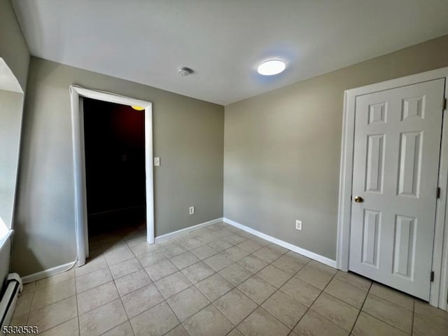 tiled empty room with a baseboard heating unit