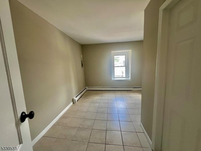 tiled empty room featuring a baseboard heating unit