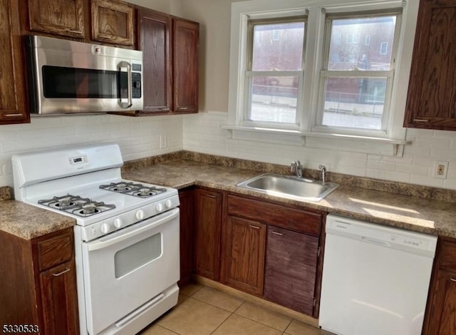 kitchen featuring decorative backsplash, white appliances, sink, and light tile patterned floors