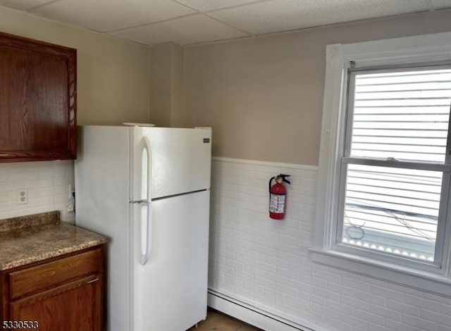 kitchen featuring a drop ceiling, white refrigerator, and a baseboard radiator