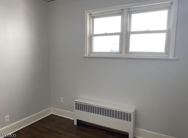 unfurnished room with dark hardwood / wood-style flooring and radiator heating unit