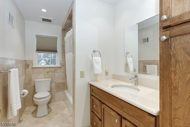 bathroom featuring vanity, toilet, and tile walls