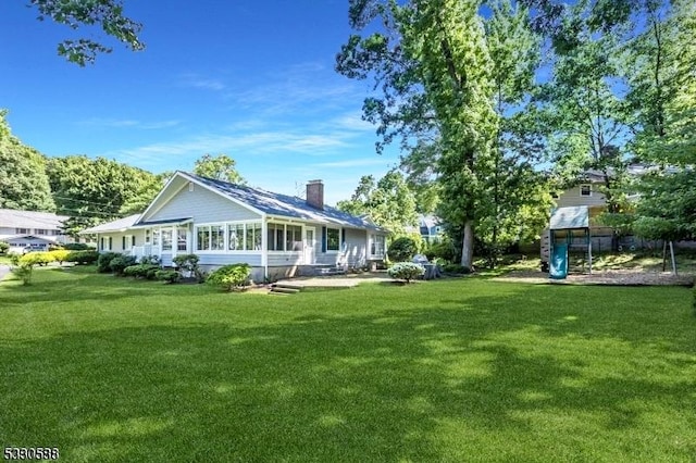 back of property featuring a lawn and a sunroom