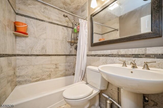 bathroom with toilet, tile walls, and shower / bath combo with shower curtain