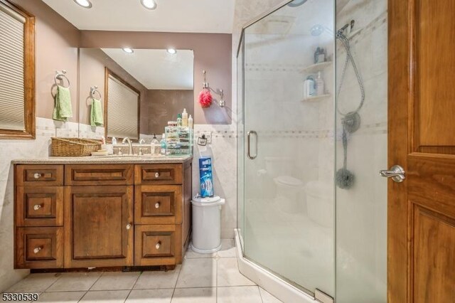 bathroom with tile patterned flooring, vanity, and walk in shower